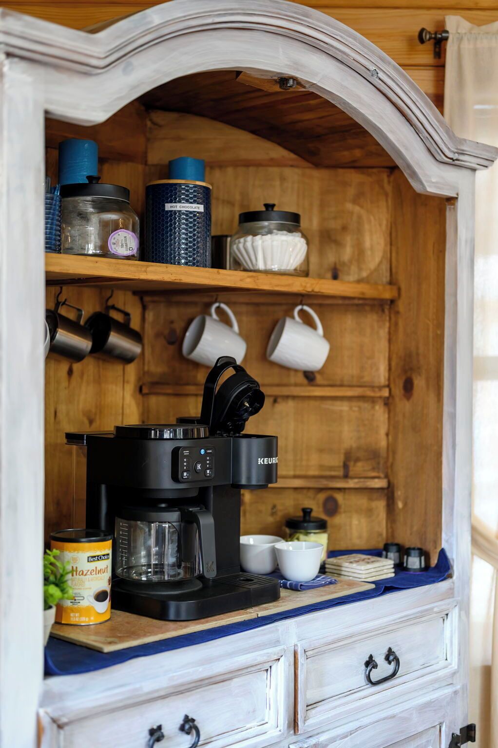 Een keuken met een koffiezetapparaat, potten en mokken op planken.