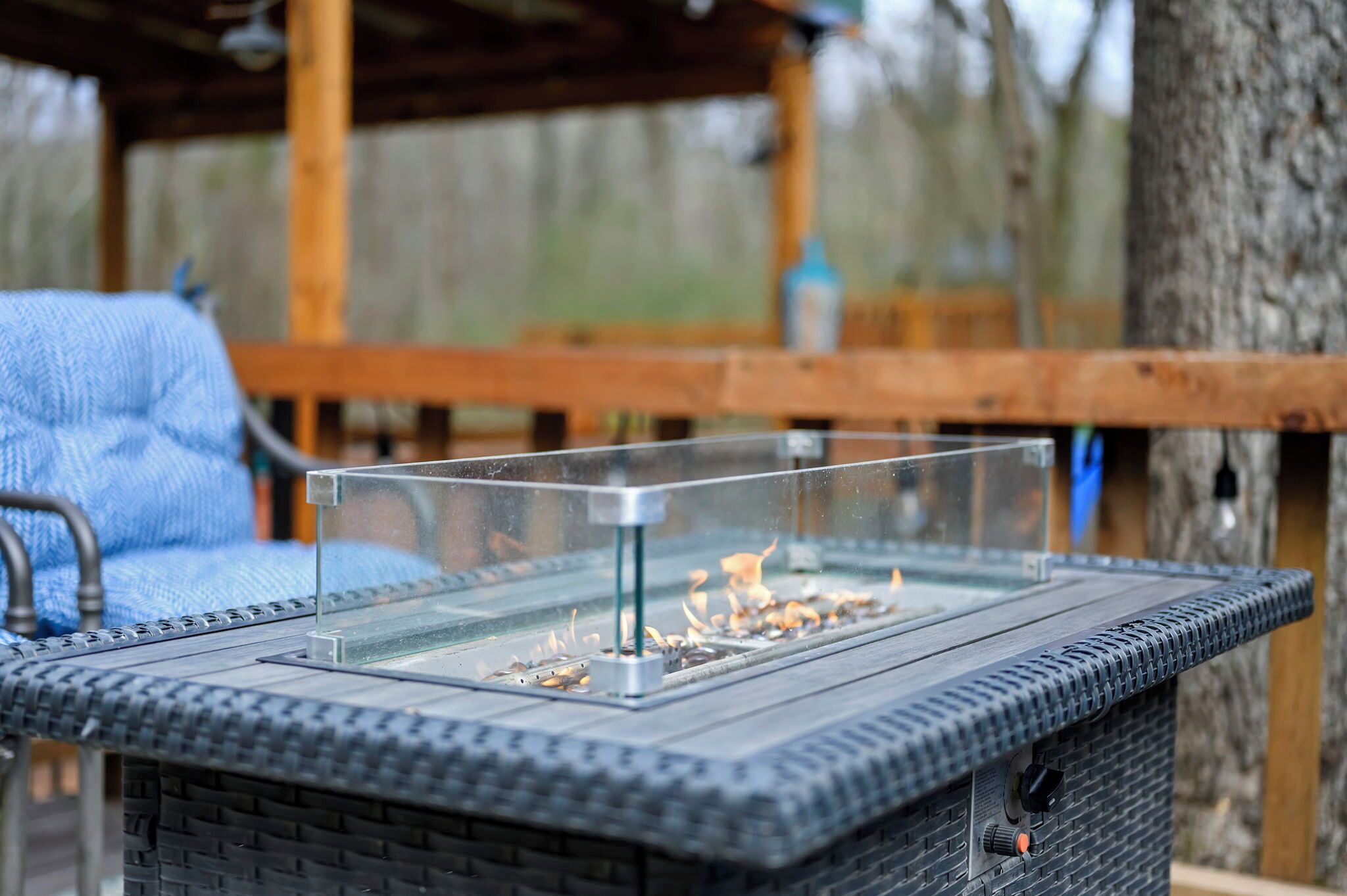 Ein Grill mit Glasplatte und Metallrahmen auf einem Korbstuhl-Tisch.