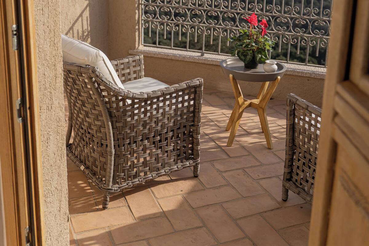 A balcony with wicker furniture, a small table, and a potted plant.