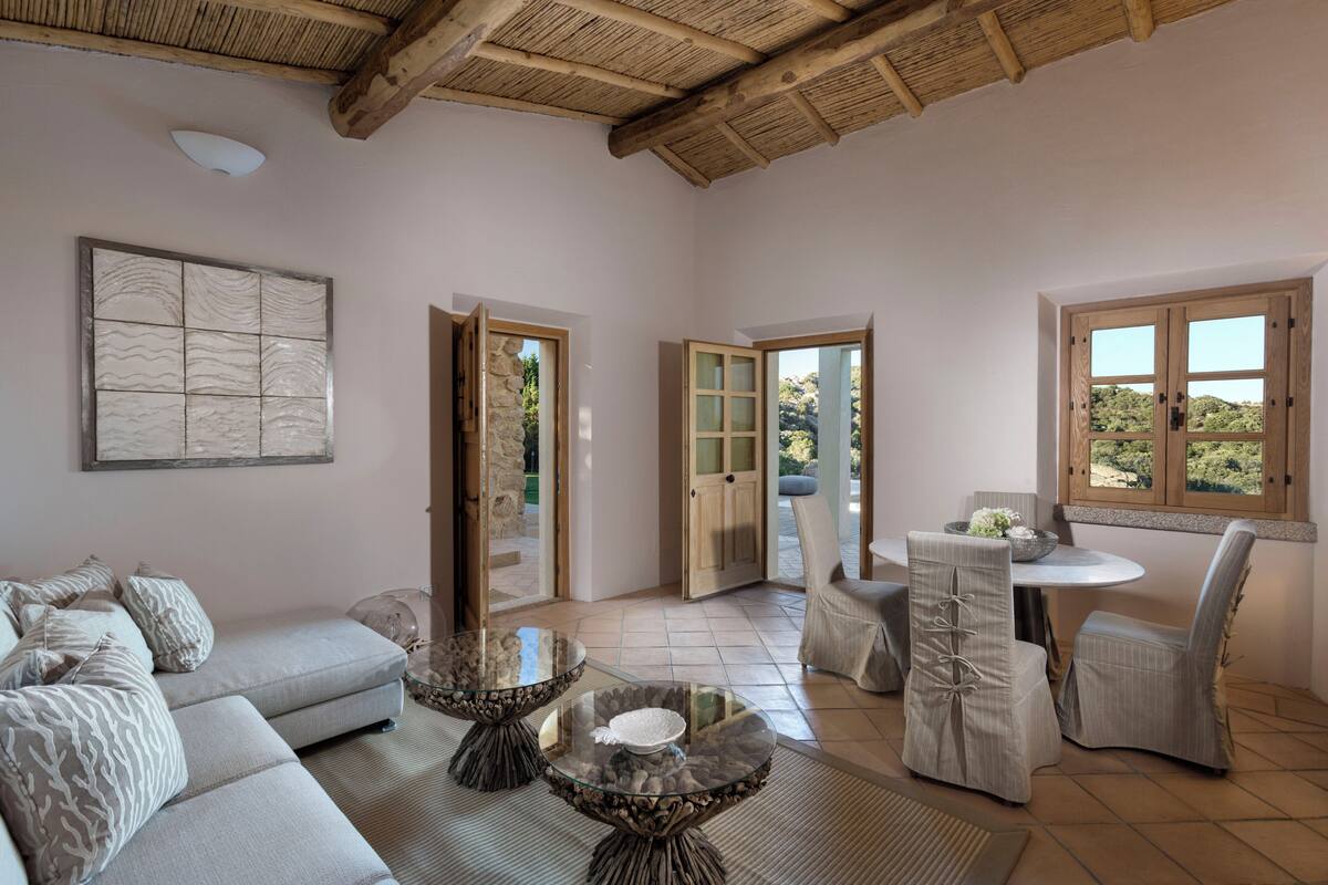 A spacious living room with a sofa, two glass-top coffee tables, and a dining area with a table and chairs.