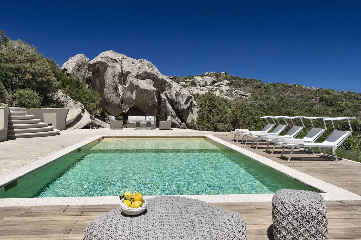A swimming pool with a view of rocky terrain and lounge chairs.