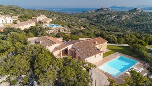Una villa con piscina, rodeada de exuberante vegetación y colinas.