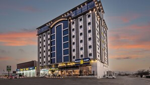 A multi-story hotel with a prominent entrance and signage for "The Palace Hotel Suites". - Al Qasr Hotel Suites - Al Wadiin (Ahad Rafidah)