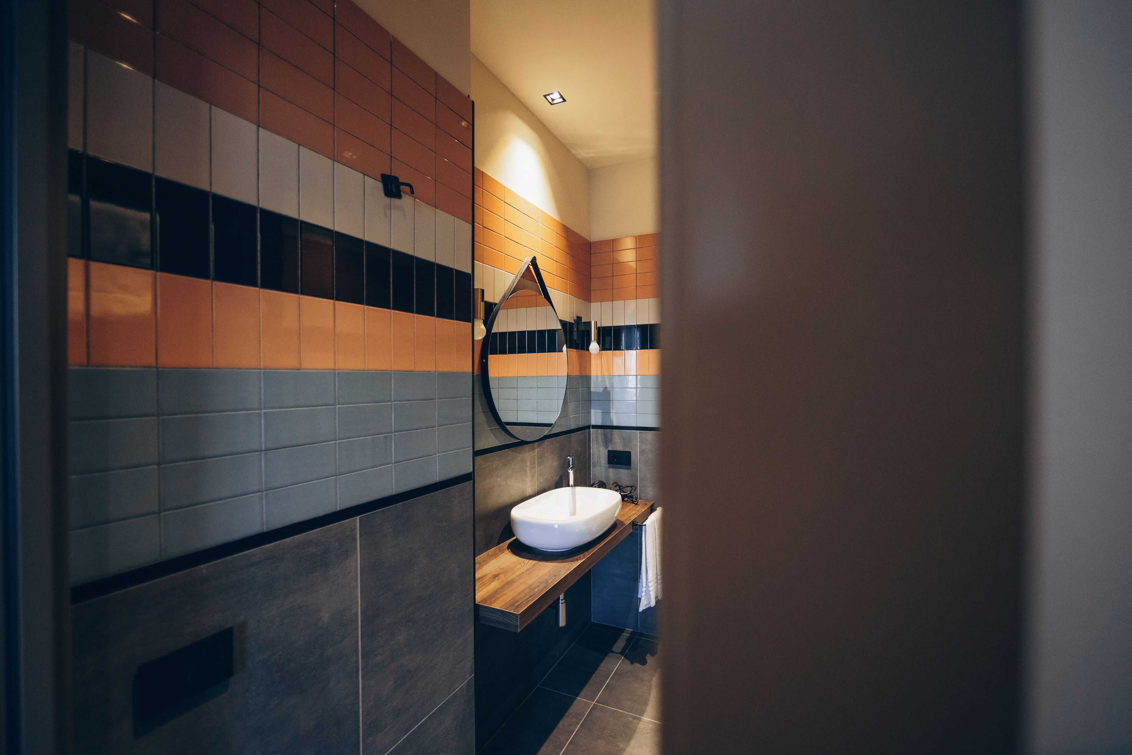 Un baño moderno con tocador de madera, lavamanos blanco y espejo.