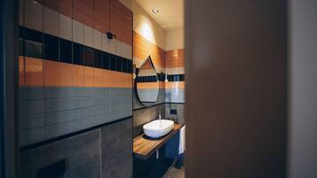 Un baño moderno con tocador de madera, lavamanos blanco y espejo.