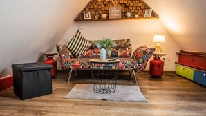A cozy living room with a colorful sofa, a small round table, and a red gas cylinder. - Tiny maisonette in the center with wifi & parking space (Nordhorn)