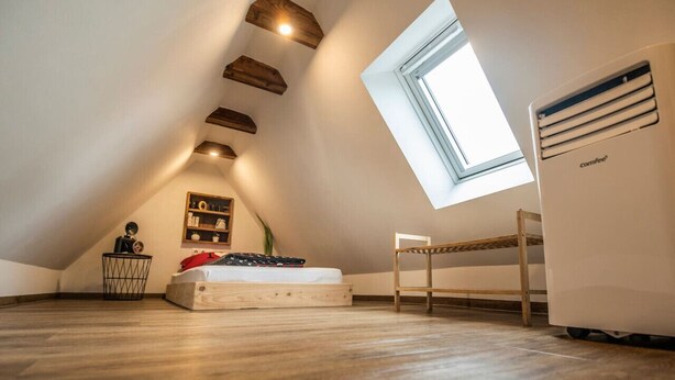 A loft bedroom with a sloped ceiling, a skylight, a Comfee air purifier, a bunk bed, and a small table. - Tiny maisonette in the center with wifi & parking space (Nordhorn)