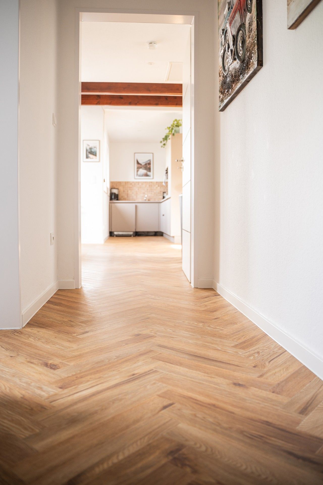 Un couloir au plancher de bois menant à une cuisine.