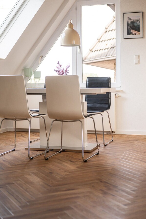 A modern interior with a sloped ceiling, two chairs, a table, and a pendant light.