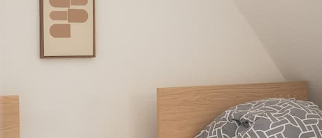 Une chambre à coucher avec un lit, une table de chevet ornée d’une plante et une œuvre d’art accrochée au mur.