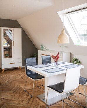 A modern dining area with a white table, black chairs, and a pendant light.