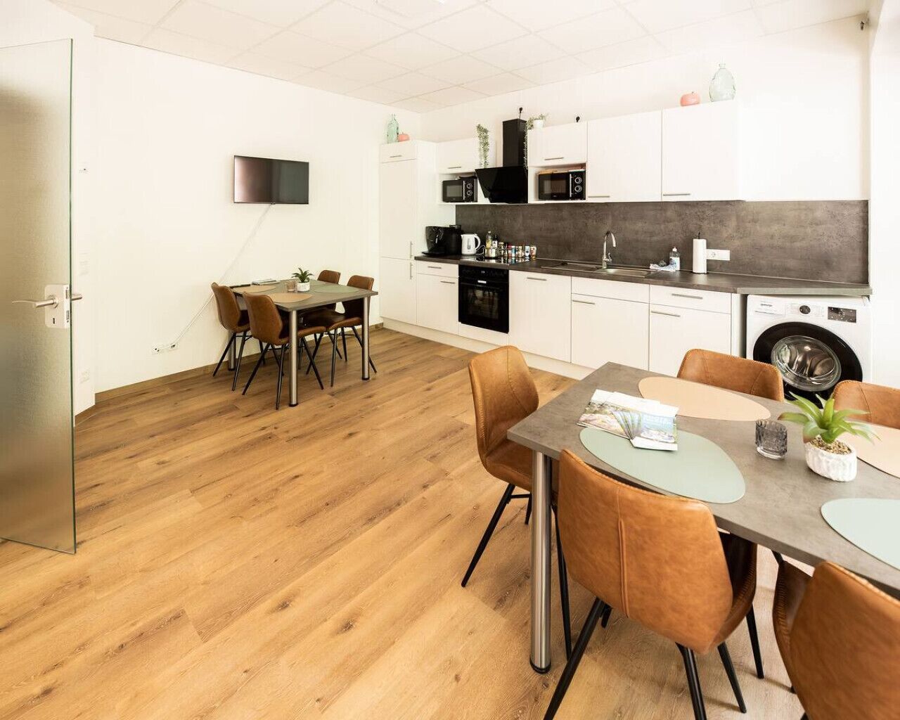 A modern kitchen with white cabinets, a black countertop, and a dining area with a table and chairs.