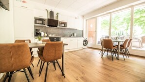 A modern kitchen with white cabinets, a microwave, and a large window overlooking a balcony.