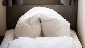 Een bed met witte lakens, een kleine potplant en een fotolijstje op een vensterbank.