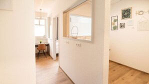 Een gang met een houten vloer, een bureau met stoel en een raam met spiegel.