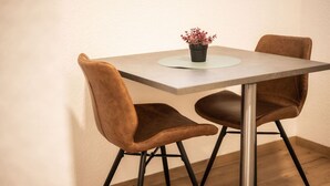 Een tafel met twee stoelen, een potplant en een lichtgekleurd tafelkleed.