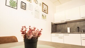 Een moderne keuken met witte kastjes, een zwart aanrecht en een potplant op de tafel.