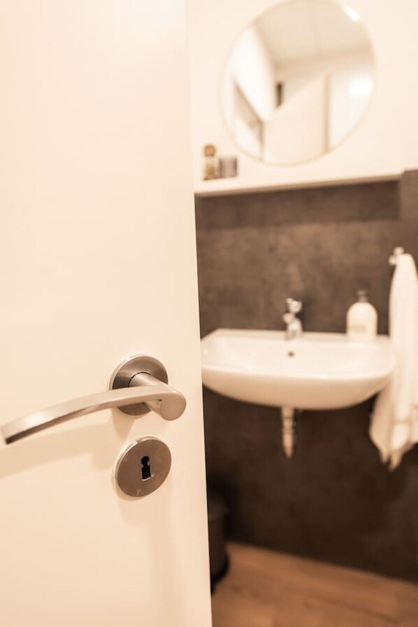 A bathroom with a white sink, a mirror above it, and a towel hanging on the wall. - FAIR BED 9 City Studio with kitchen, WLAN, 2 rooms & PP (Nordhorn)