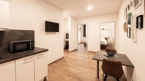 A modern kitchen with a microwave, white cabinets, and a dining area with a table and chairs. - FAIR BED 9 City Studio with kitchen, WLAN, 2 rooms & PP (Nordhorn)