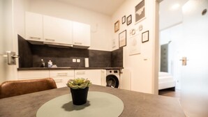 Una cucina moderna con mobili bianchi, un piano di lavoro nero e una lavatrice sullo sfondo.