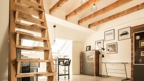 A spacious kitchen with wooden beams, a wooden ladder, and a dining area with a table and chairs. - Central studio - loft with WLAN & parking space (Nordhorn)