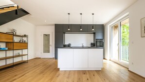Una cocina moderna con una isla central, luces colgantes y vistas al exterior.