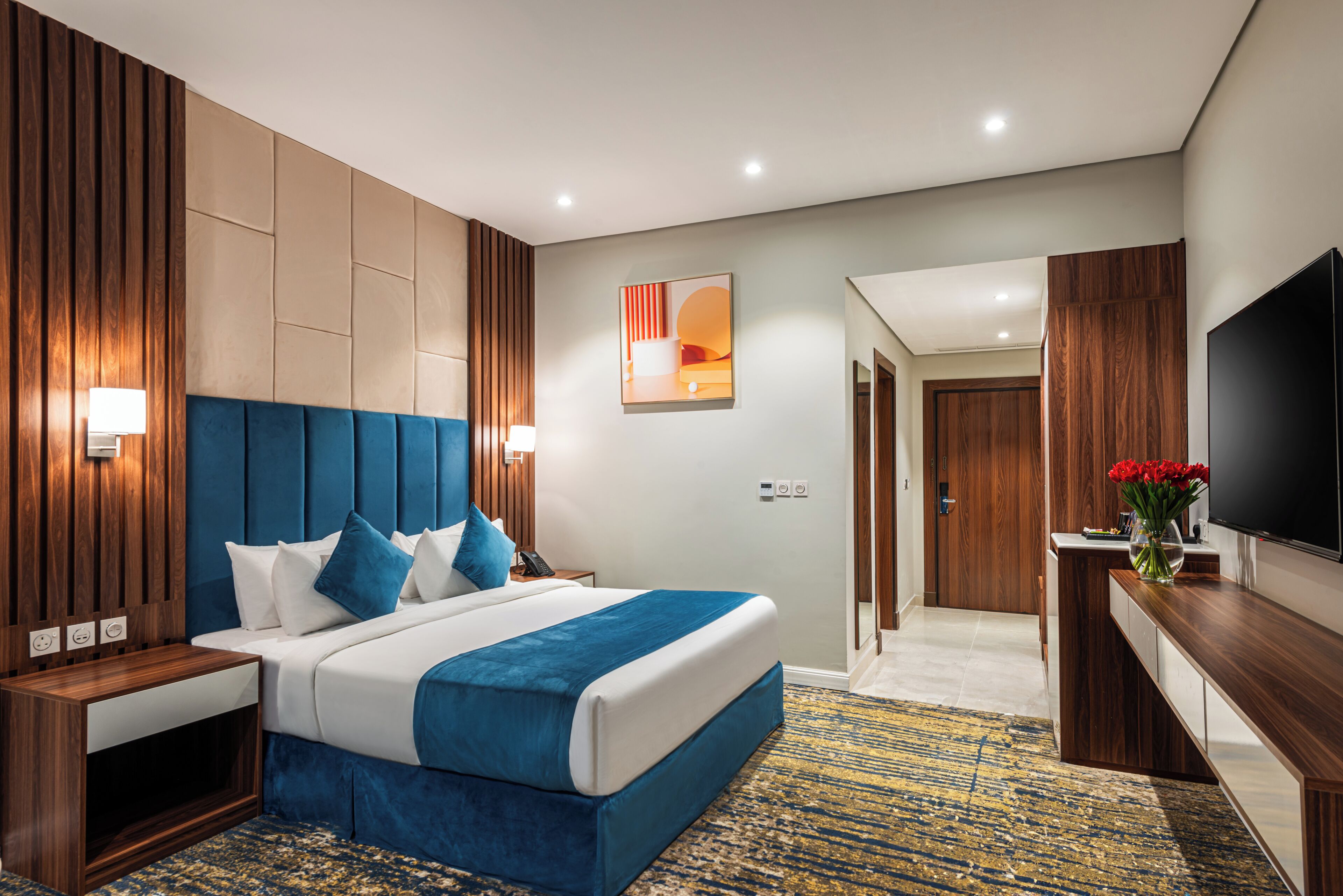 Una habitación de hotel moderna con una cama grande, televisión, escritorio y vestidor.