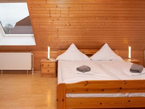 A wooden-paneled bedroom with a bed, two bedside tables, a radiator, and a skylight. - Stunning  villa for 4 people with WIFI, TV and terrace (Norden)