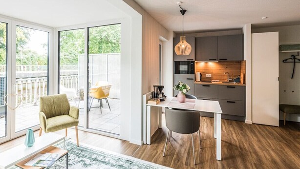 A modern kitchen with a dining area, large windows, and a balcony. - "Vechte-Garten" new build with a view of the water & PP (Nordhorn)