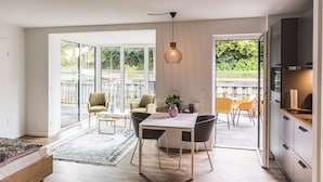 A modern kitchen with a dining area, large windows, and a view of the outdoors. - "Vechte-Garten" new build with a view of the water & PP (Nordhorn)