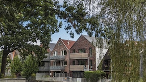 A canal-side building with a brick facade, multiple balconies, and a small boat docked in front. - "Vechte-Garten" new build with a view of the water & PP (Nordhorn)