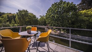 A terrace with yellow chairs and a table, overlooking a canal and trees. - Vechte view studio, new building with balcony, WLAN & PP (Nordhorn)