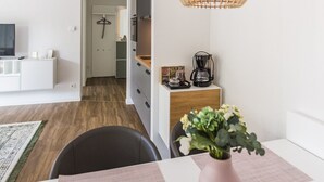 A modern living room with a dining area, a kitchen in the background, and a hanging light fixture. - Vechte view studio, new building with balcony, WLAN & PP (Nordhorn)