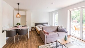 A modern, well-lit room with a dining table, chairs, a sofa, and a bed. - Vechte view studio, new building with balcony, WLAN & PP (Nordhorn)