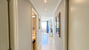 Un pasillo con piso de mármol, paredes blancas e iluminación empotrada.