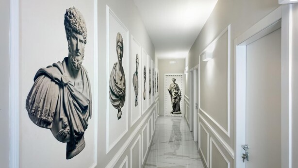 Un couloir orné de statues en marbre le long des murs et doté d’un sol poli.