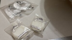 Un lavabo de salle de bain avec des articles de toilette, notamment un bonnet de douche, un flacon de savon liquide et trois tubes de lotion pour le corps.