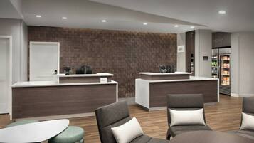 A modern reception area with two counters, seating, and a refrigerator stocked with beverages.