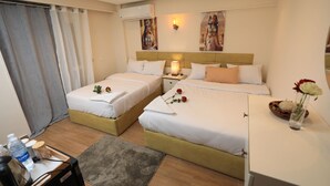 A hotel room with two beds, a desk, a chair, a small table with a vase of flowers, and a window with curtains. - Pyramids Heart Hotel (Giza)