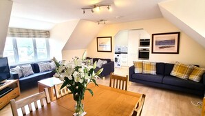 Ein modernes Loft-Apartment mit Essbereich, zwei Sofas, einem Fernseher und einer Küche.