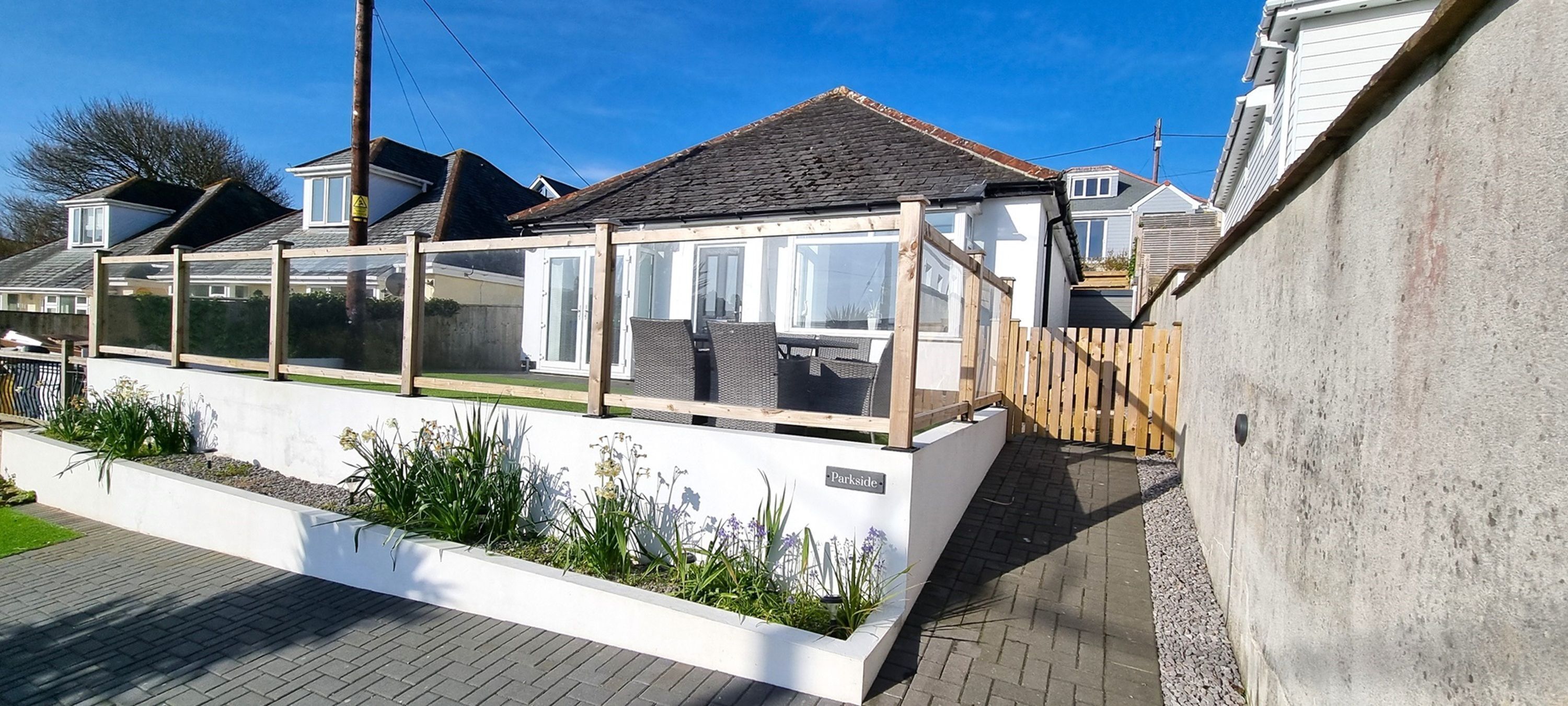 A modern house with a conservatory, a paved driveway, and a garden area.