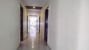 A long, narrow hallway with a polished floor and white walls. - Hotel Yash Raj (Sihora)