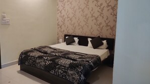 A bedroom with a bed, a patterned bedspread, and a floral wallpaper. - Hotel Yash Raj (Sihora)