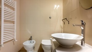 A bathroom with a bidet, a toilet, and a large vessel sink.