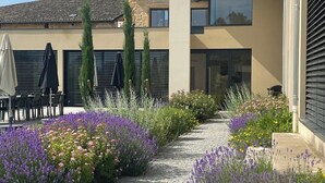 A courtyard with a cobblestone path, outdoor seating, and a building with large windows and a tiled roof. - Villa Molinant, escape in Golden Stones (Bagnols)