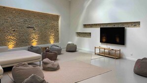 A modern living room with a stone accent wall, a flat-screen TV, and multiple bean bags. - Villa Molinant, escape in Golden Stones (Bagnols)