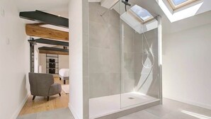 A modern bathroom with a glass-enclosed shower, a skylight, and a wooden ceiling beam. - Villa Molinant, escape in Golden Stones (Bagnols)