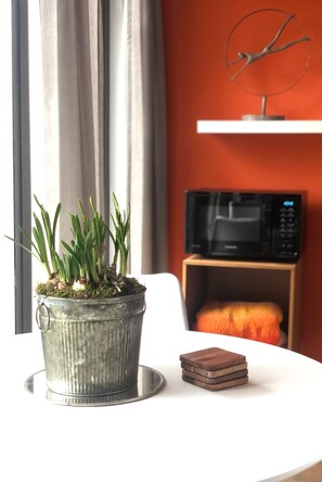 A potted plant on a table, a microwave, and a shelf with a decorative item.