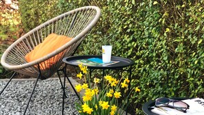 A patio area with outdoor furniture, a table with a cup and a book, and a potted plant with yellow flowers. - Luxe studio with vintage look in  ‘a New Village on New Land’ Nagele (Nagele)