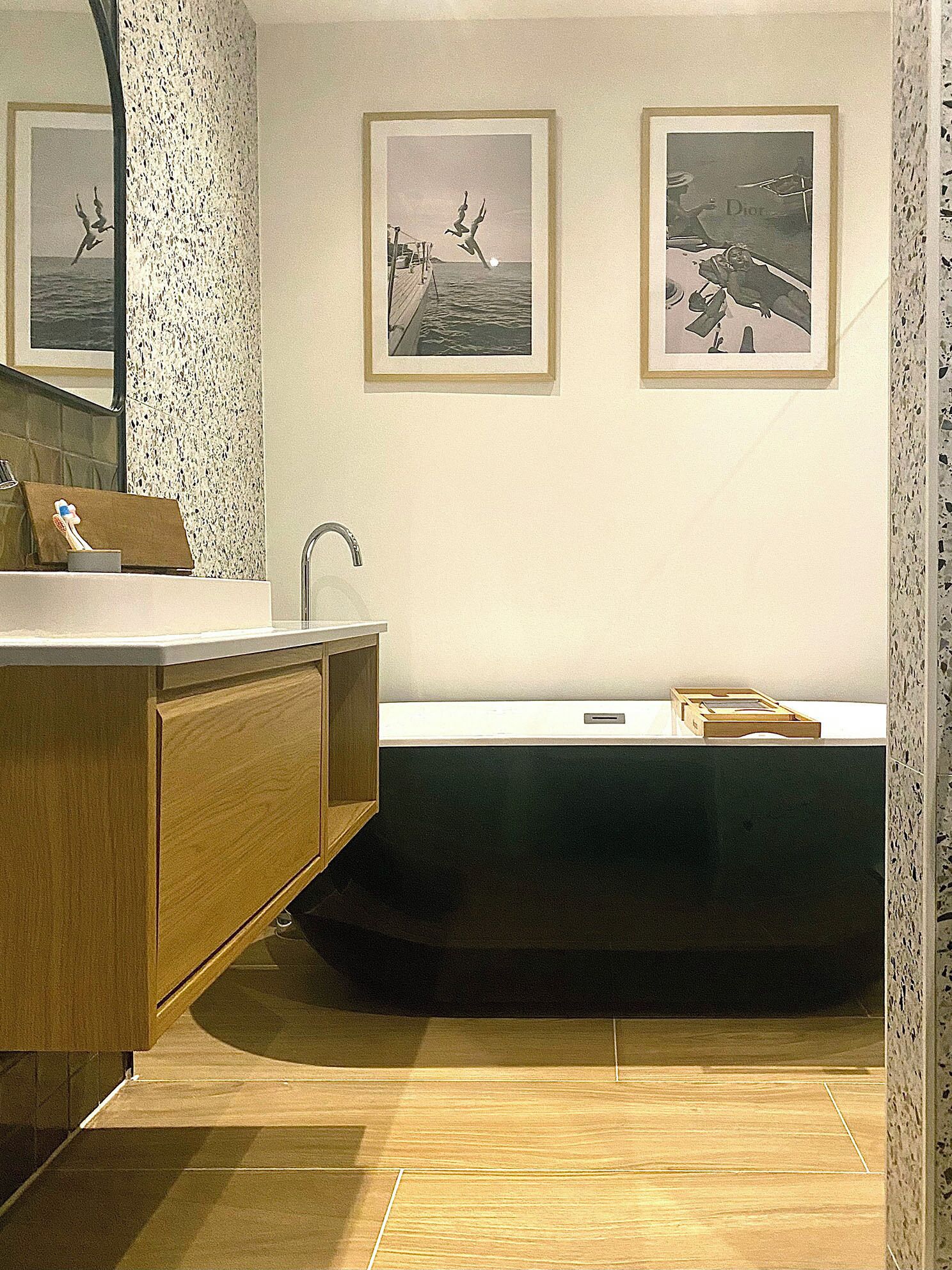 A bathroom with a wooden vanity, a freestanding sink, and two framed pictures on the wall.